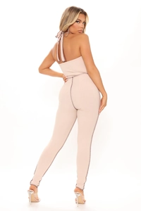 Detail of a backless halter jumpsuit in oatmeal ribbed knit with contrast stitching