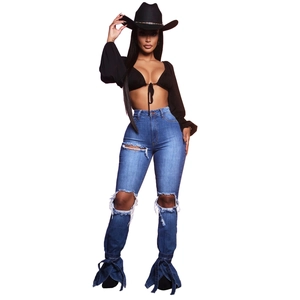 Dettaglio dei jeans a zampa blu con fiocchi laterali e design strappato al ginocchio