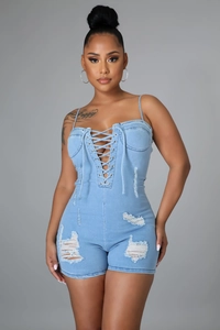 Détail de la barboteuse en denim bleu clair avec laçage frontal et texture déchirée