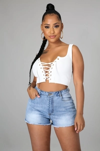 Gros plan sur un short en jean bleu clair avec bords effilochés et détails de lacets à œillets