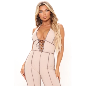 Close-up of beige ribbed halter jumpsuit with contrasting dark stitching and tie-up neckline