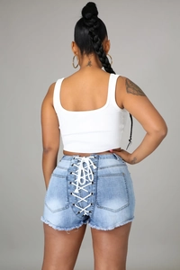 Détail du short en jean bleu clair avec lacets, œillets et ourlet à bords francs
