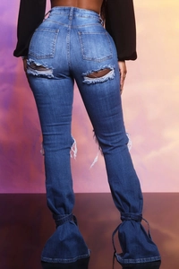 Dettaglio jeans blu strappati con tagli sulle tasche e lacci sulle caviglie