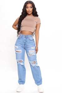 Dettaglio dei jeans a vita alta a gamba larga con strappi e finiture in denim sfilacciato