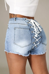 Détail du short en jean bleu clair avec laçage à œillets et ourlet effiloché à l'arrière