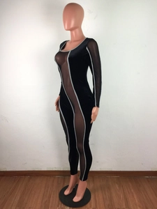Detailansicht eines schwarzen Samt-Jumpsuits mit Mesh-Einsätzen und weißen Paspelkonturen