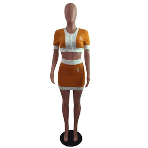 Detail view of orange and white two-piece skirt set with SJ letter logo and buttons