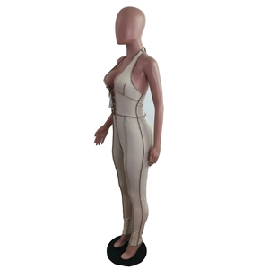 Detail of ribbed beige jumpsuit featuring deep V-neckline with brown contrast stitching