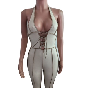 Detail of ribbed knit jumpsuit featuring a deep V-neck and brown cross-lace chest ties