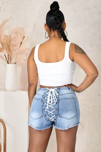 Détail du short en jean bleu clair avec laçage blanc et œillets sur l'arrière