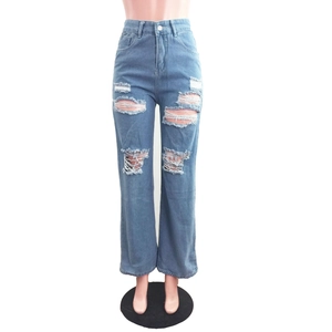 Dettaglio macro di jeans a vita alta blu chiaro con strappi decorativi e bordi sfilacciati