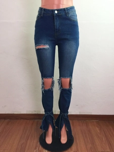 Dettaglio di jeans a zampa con fori usurati e spacco laterale con fiocco decorativo