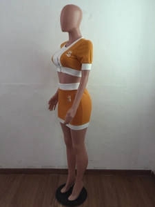Detail of yellow crop top and mini skirt set with white piping and logo graphics