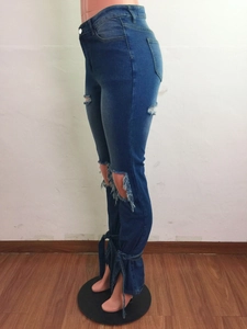 Dettaglio dei jeans blu a vita alta da donna con spacchi laterali e lacci sulla caviglia