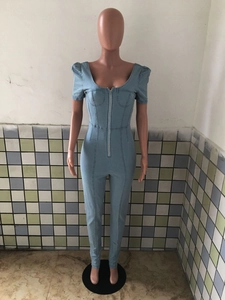 Detail of light blue denim slim fit jumpsuit with puff sleeves and front zipper closure