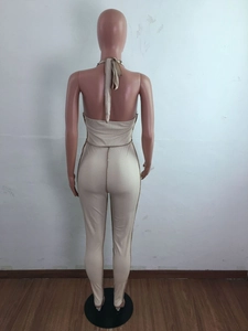 Detail view of the backless halter jumpsuit in beige ribbed knit with tie-back design