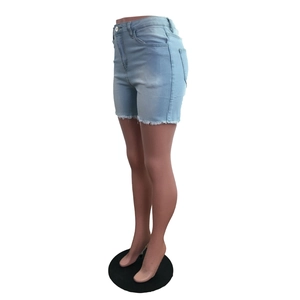 Détail d'un short en jean bleu clair avec bords effilochés et fermeture à bouton latéral