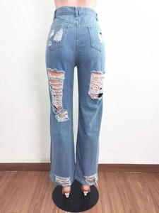 Dettaglio di jeans azzurri a vita alta e gamba larga con strappi e finitura usurata