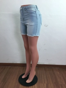Détail du short en jean bleu clair à taille haute avec bords effilochés et coupe ajustée