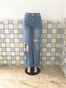 Détail des déchirures prononcées sur ce jean en denim bleu clair pour femme au style usé