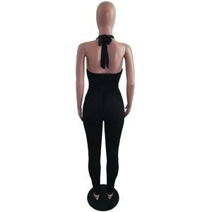 Detail of the backless halter jumpsuit featuring black ribbed knit fabric and tie design