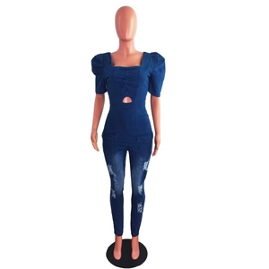 Close-up of waist cutout and distressed denim detail on blue slim fit jumpsuit