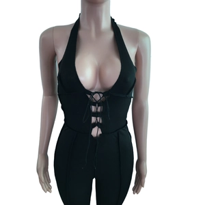 Detail view of black ribbed halter jumpsuit with deep V-neck and lace-up front design