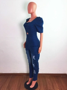 Detail of slim fit denim jumpsuit with waist cut-out, puff sleeves and distressed holes