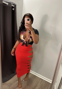 Detail of red high-waist maxi skirt with side cut-out rings and waist tie design