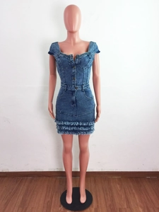 Dettaglio dell'abito in denim azzurro con orlo sfrangiato e bottoni sulla parte anteriore