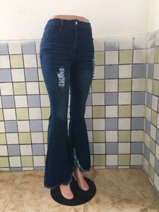 Detailansicht der Schlagjeans mit Distressed-Knien und ausgefransten Quastensäumen am Bein