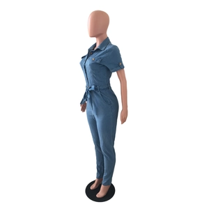 Detail view of denim jumpsuit with short sleeves, collar, front pockets, and a tie waist belt