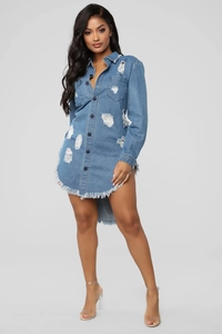 Close-up of distressed denim shirt dress with ripped holes and raw fringe hem details