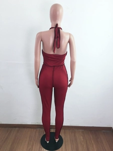Detail view of dark red ribbed knit fabric on a backless halter jumpsuit with bow tie