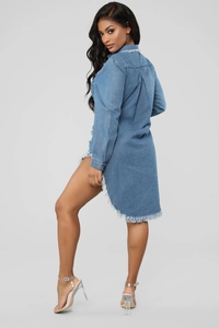 Close-up of distressed fringe hem and asymmetrical high-low cut on denim shirt dress