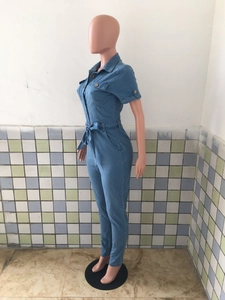 Side view of light blue denim jumpsuit featuring short sleeves and a belted waistline