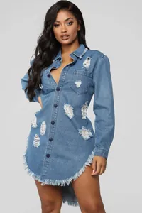 Close-up of distressed light blue denim dress with ripped details and frayed hem