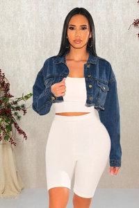 Détail de veste courte en jean bleu foncé avec ourlet effiloché et boutons dorés