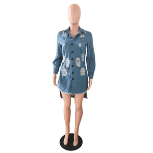 Detail of blue denim shirt dress with ripped distressed patterns and fringe hem