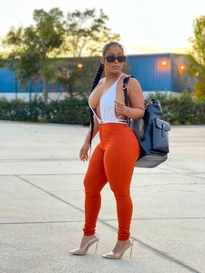 Detail of high waist stretch skinny trousers in orange paired with a white bodysuit