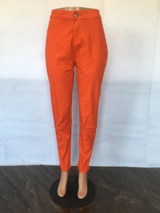 Detail of high waisted orange skinny jeans with bronze button closure and slim fit design