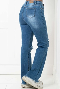 Close-up of blue flared jeans with knee distress and raw hem finish details
