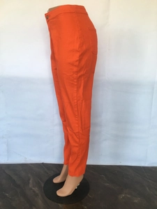 Detail shot of bright orange high-waisted denim pants with button and back pocket design