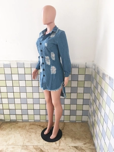 Detail view of distressed light blue denim dress featuring raw tassel hem and ripped accents