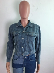 Détail d'une veste en jean bleue à franges et d'un jean avec patchwork asymétrique