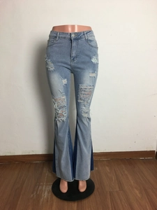 Detail of light blue washed flare jeans with distressed rips and contrast denim side panels