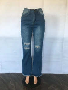 Detail view of distressed dark blue flared jeans with ripped knees and frayed hem