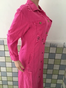 Detail eines rosafarbenen Denim-Mantelkleids mit Distressed-Löchern und Goldknöpfen