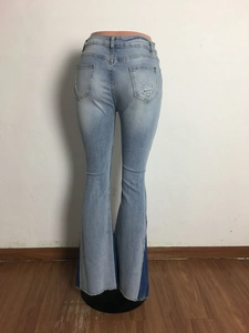 Detail of light blue washed flare jeans featuring ripped back pocket and side splicing