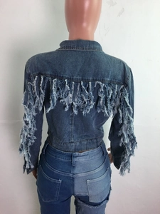 Détails de la veste en jean bleu foncé montrant les franges et les éléments usés